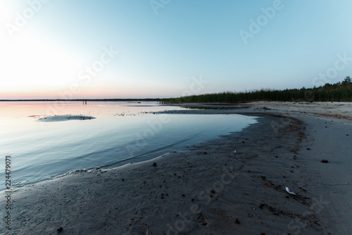 Beautiful  red dawn on the lake. The rays of the sun through the fog. The blue sky over the lake  the morning comes  the sky is reflected in the water.