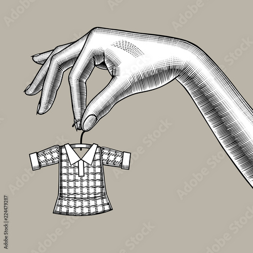 Female hand holding a tiny little dress on hanger