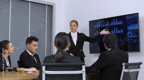 Business girl explaining graph on Monitor screen to the Colleagues in meeting room. 