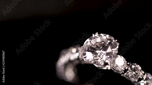 Engagement diamond ring rotating on black background, macro with shallow DoF