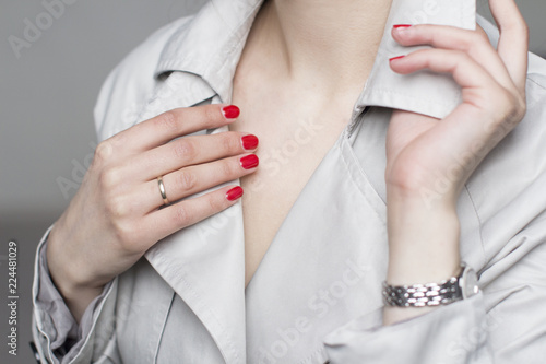 young woman with red nail polish wearing beige trenchcoat and silver wrist watches photo