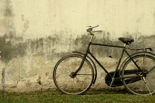 Retro Rusty Black Bicycle against Old Damaged Plaster Wall - Vintage Effect Style Image