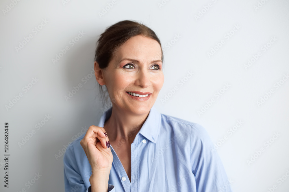 Fototapeta premium Beautiful mature woman smiling.Close up portrait of beautiful older woman smiling and standing by wall.Portrait of business woman with glasses smiling.