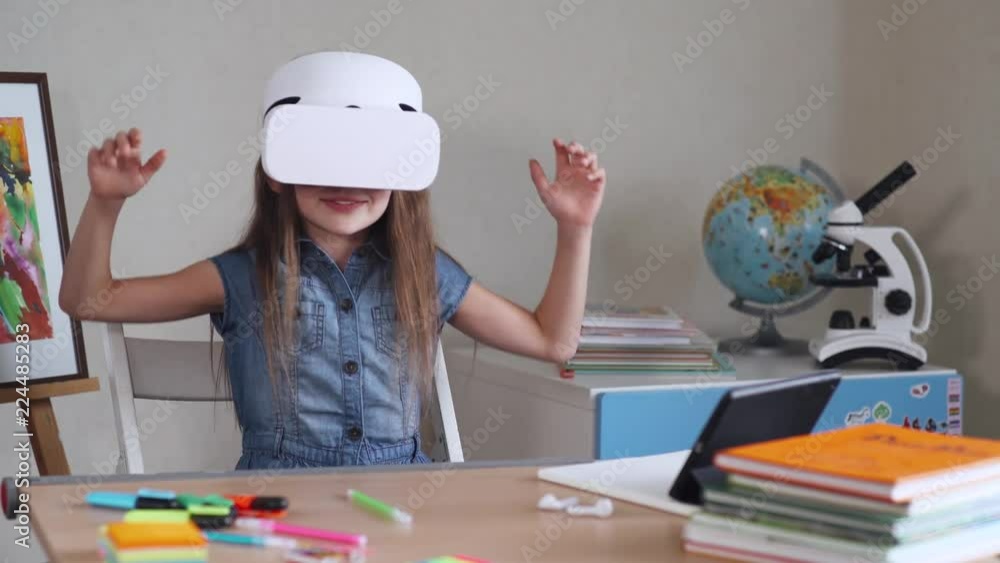 Schoolgirl plays a game in virtual reality glasses, positive emotions, futuristic white goggles. Schoolgirl plays a game in virtual reality glasses, positive emotions, futuristic white goggles.