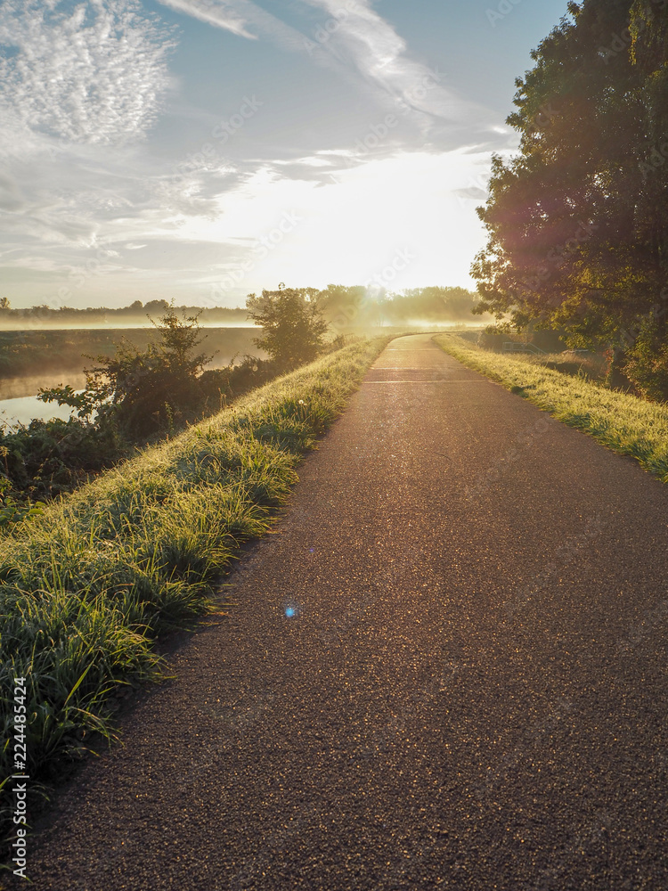 Gorgeous sunrise over the pathway next the river Dyle near Mechelen, Belgium, during an early misty morning in September