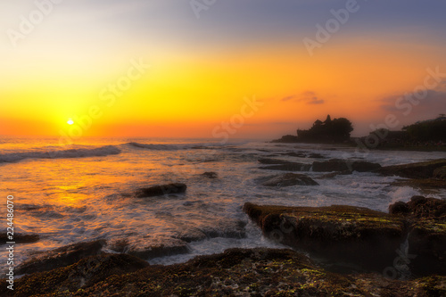 Pura Tanah Lot temple on the beach at sunset in seaside of Bali island. Shilouette of a temple