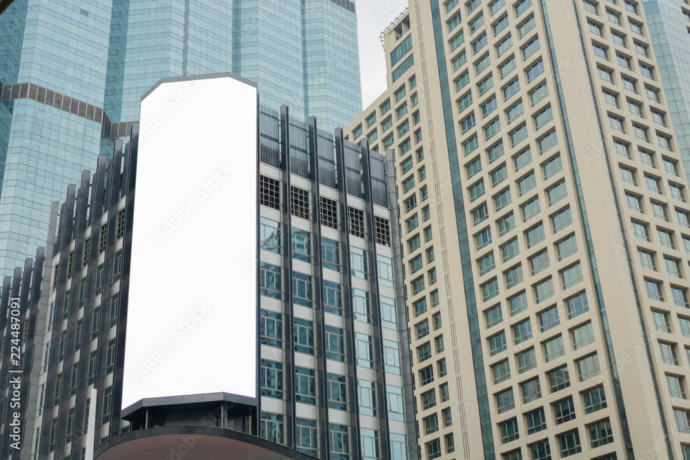 Obraz premium Blank advertising billboard on the Glass wall in a modern office building, Common business skyscrapers, high-rise buildings, architecture raising to the sky, the sun light reflected on the structure