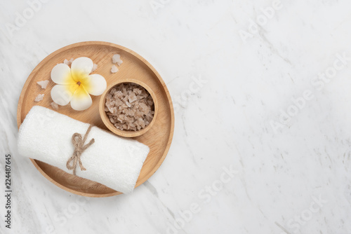 Top view of Spa products in wooden tray in round shape on white marble.