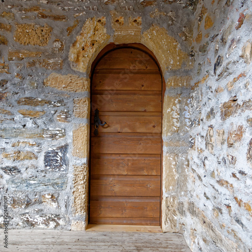 old wooden arched door on stone wall