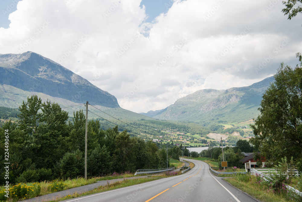 Naklejka premium scenic view of road and mountains under cloudy sky, Hallingskarvet National park, Norway