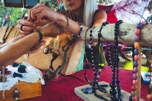 Tela A woman selling homemade craft jewelry from a market stall at a hippy festival