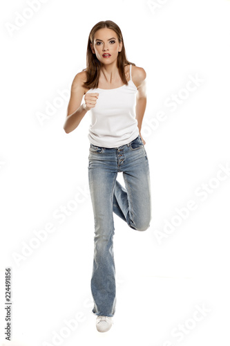 Young pretty woman running in bell bottom jeans on white background