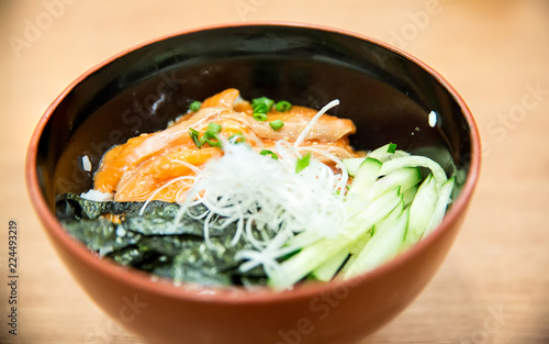 salmon slice took by chopsticks. salmon topped by fresh salmon served with wasabi and soy sauce, donburi rice. image for background, copy space, decorate and menu list.