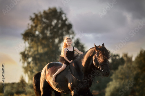 Little ballerina girl with black friesian stallion 