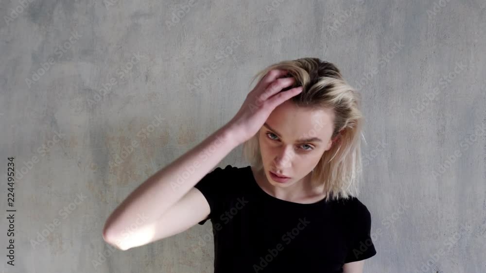 fashionable woman blonde poses with hair on a grey background