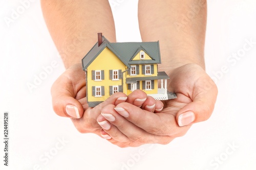 Women's Cupped Hands Holding a Model of a House