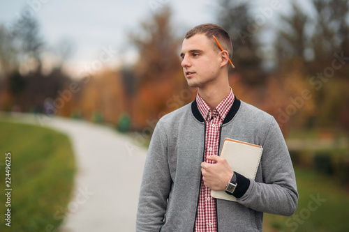 A cute student writes down his thoughts in his notebool using a pensil photo