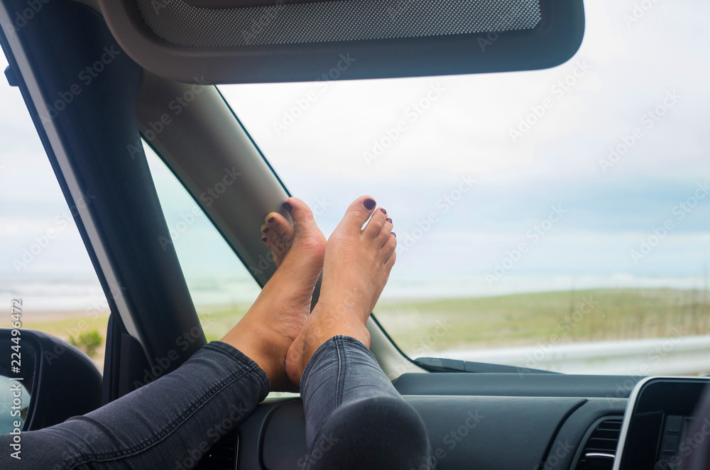 Girl lifting her tired feet during a long trip by car. Manage jet lag