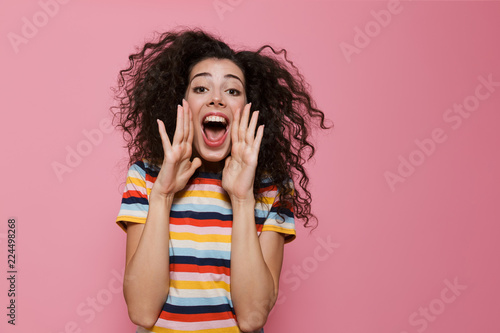 Фотография Image of young woman 20s with curly hair shouting or calling, isolated over pink