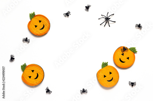 Flat lay Halloween background with decorative pumpkins and spiders on white background. Blank space for text.