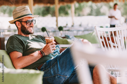Young man drinking ice coffee in a beach bar