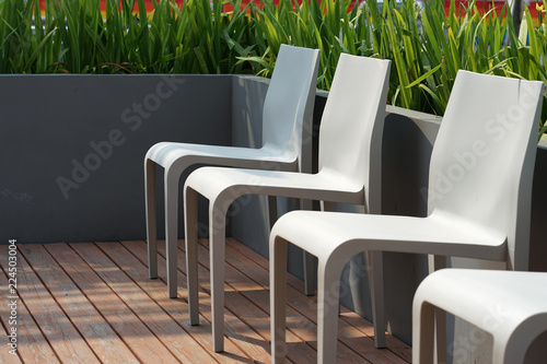 Obraz na płótnie Grey plastic chairs on the timber terrrace with planter box background w salonie