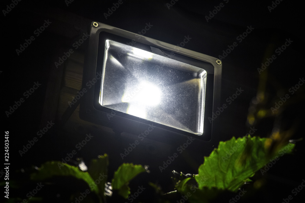 Garden LED spotlight on a wooden building close-up. - obrazy, fototapety, plakaty 