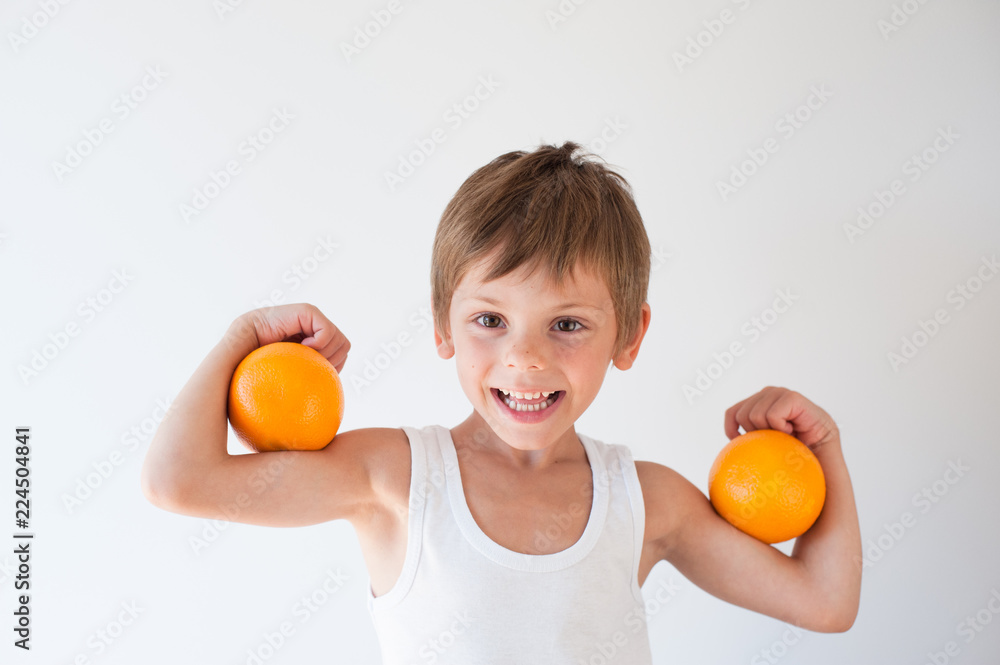 happy delightful smiling little strong child with fruit orange on his muscles happy delightful smiling little strong child with fruit orange on his muscles