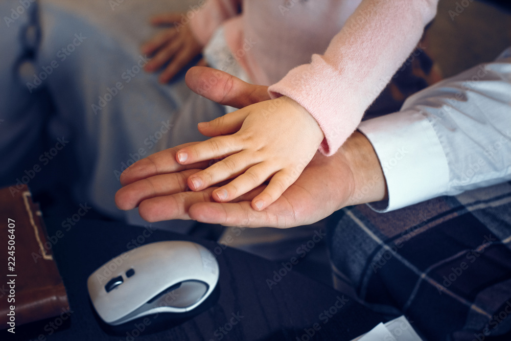 Close up hands of father and his daughter spending time at home. Family love concept.