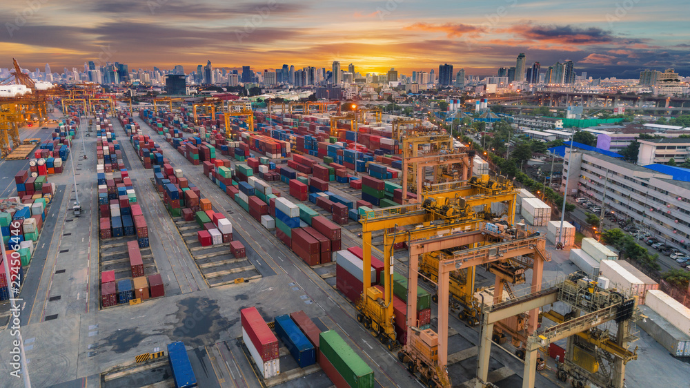 Fototapeta premium Container warehouse from sea port of ship container with beautiful sky and downtown of cityscape background. Can use for import export, international shipping concept.