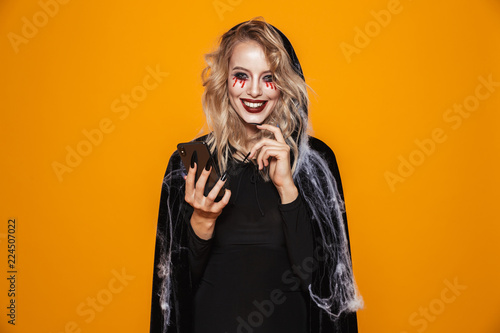 Cheerful woman witch looking camera and holding smartphone in hands