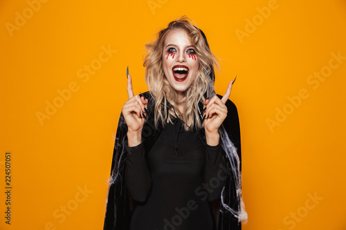 Happy witch looking and pointing up at copy space