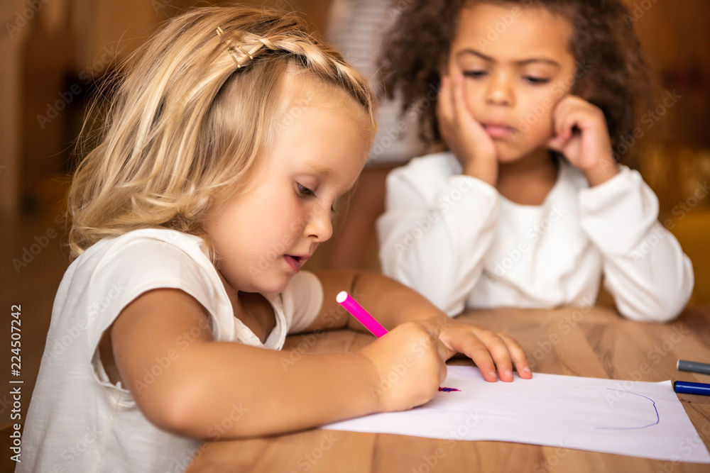 african american kid looking at caucasian child drawing at table in kindergarten african american kid looking at caucasian child drawing at table in kindergarten