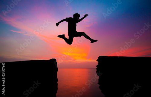 man jump over through on the gap of hill silhouette light, blue sky and sun on background.image for spirit and brave concept.spirit man is representative of success in the past and gold for the future © kanpisut
