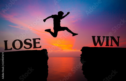 man jump over through the gap between word lose and win on hill.image for background. jump through on now to next concept. spirit man is representative of success in the past and gold for the future