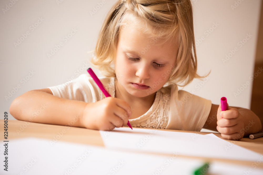 serious adorable kid drawing with pink felt pen in kindergarten serious adorable kid drawing with pink felt pen in kindergarten