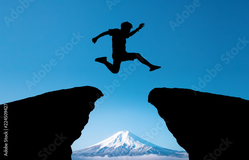 young man jump over the sun and through on the gap of hill silhouette evening colorful sky.image for spirit brave concept.man is representative of success in the past and gold for the future in 2019