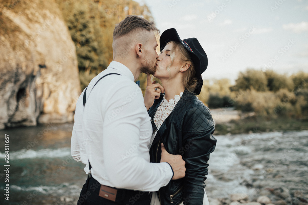 Hipster wedding couple is kissing in mountains