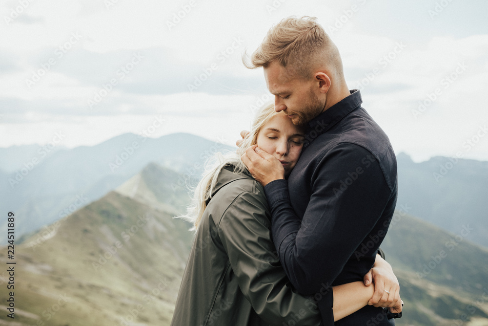 Portrait of hipster couple on the top of mountains enjoying mountains and clouds landscape. Love and travel concept. Lifestyle concept. family active traveling. Mountain view Portrait of hipster couple on the top of mountains enjoying mountains and clouds landscape. Love and travel concept. Lifestyle concept. family active traveling. Mountain view