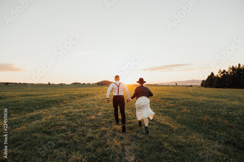 Hipster wedding couplekissing on the sunset on green field