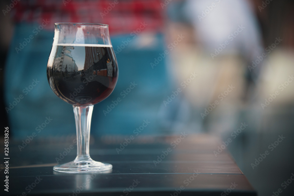 Glass of wine is on the table. The glass reflects the city street Glass of wine is on the table. The glass reflects the city street