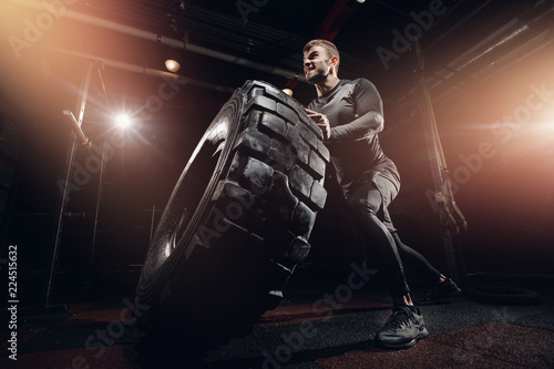 фотографія Muscular fitness man moving large tire in gym center, concept lifting, workout t