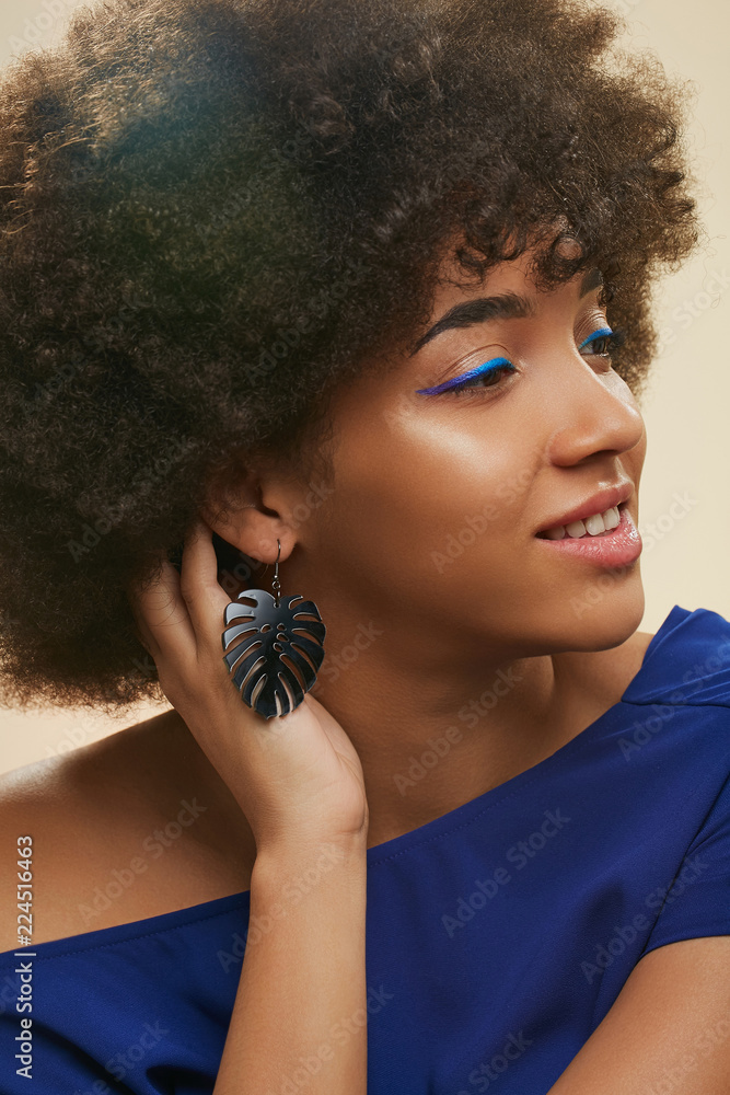 Young African lady with short curly hair. The beautiful girl in navy blue  top, wearing blue