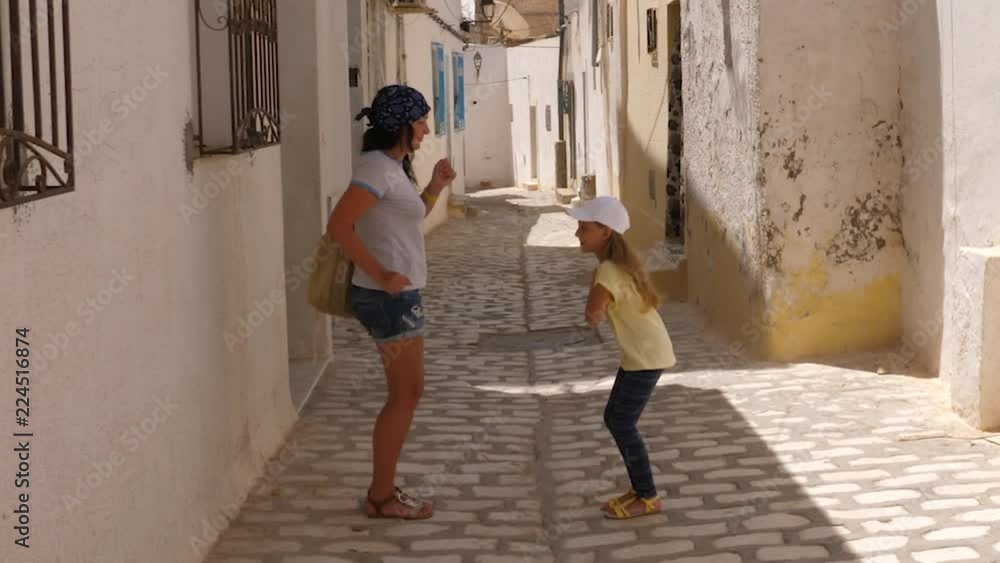 Funny mom and daughter dancing like little duck while walk along city street