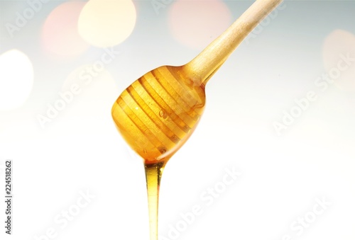 Honey with spoon in glass bowl on glossy background