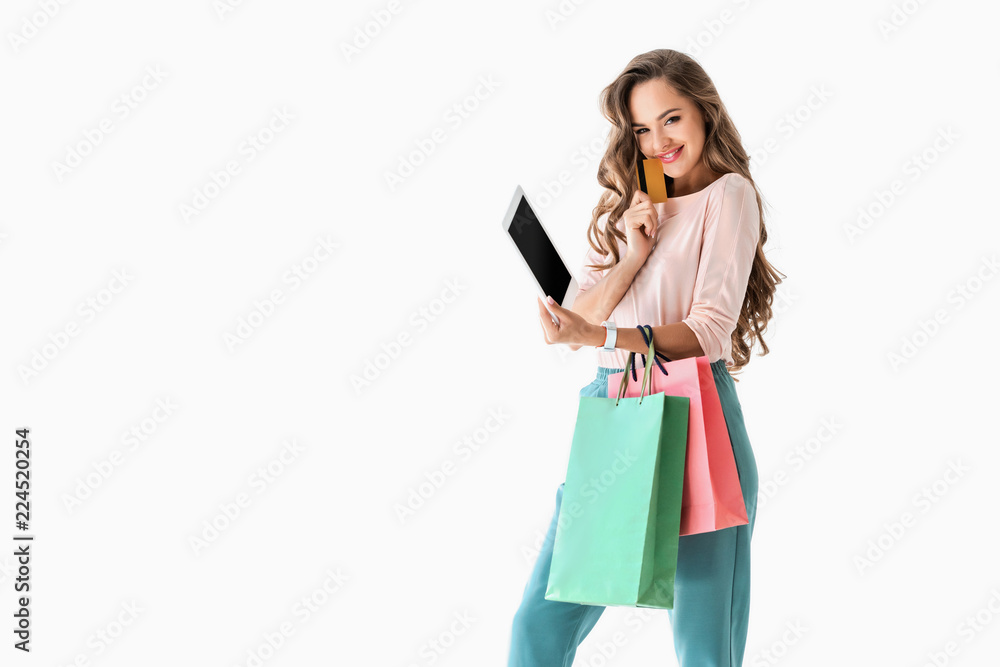 young smiling woman with shopping bags shopping online with tablet and credit card, isolated on white young smiling woman with shopping bags shopping online with tablet and credit card, isolated on white