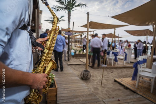 saxophonist plays a wedding party on the beach. a musician playing a classic beach party instrument.