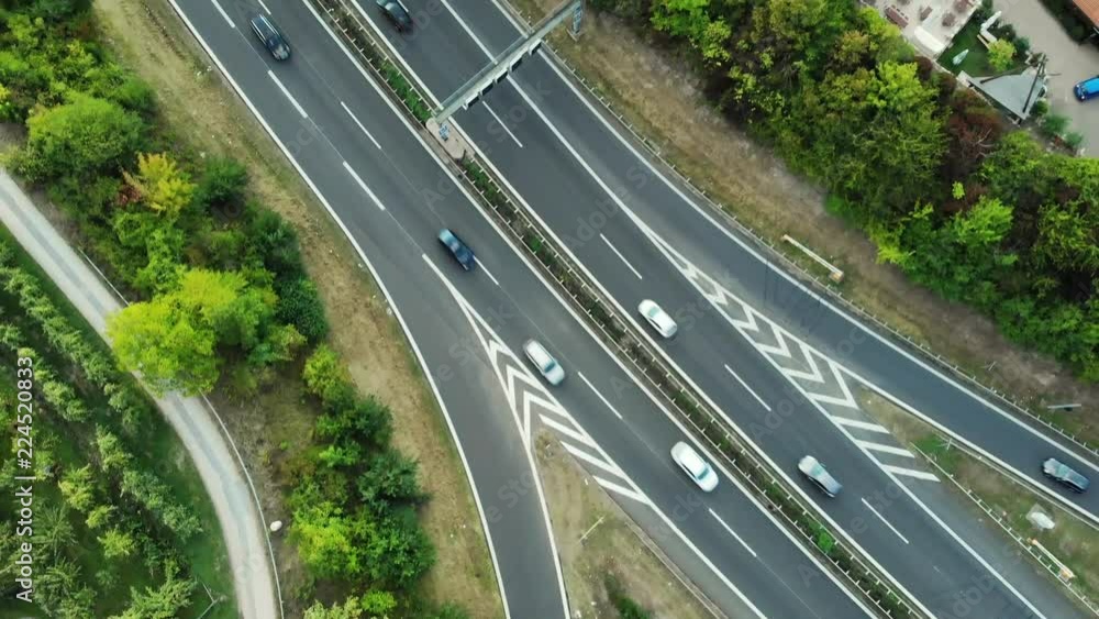 Top-down view of busy traffic flow at a highway. Beautiful greenery landscaping along the highway. Top-down view of busy traffic flow at a highway. Beautiful greenery landscaping along the highway.