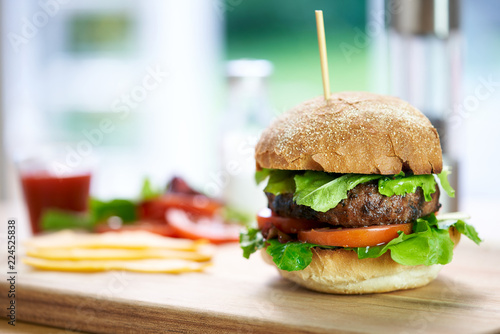 Obraz na płótnie A beef burger in a crusty bun with lettuce and tomatoes on a cho w salonie