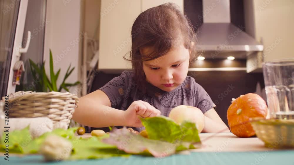 Crane shot. Autumn. Little girl sitting at the desk makes necklace of acorns Crane shot. Autumn. Little girl sitting at the desk makes necklace of acorns